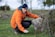 a man in an orange jacket leaning on a rock