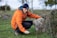 a man in an orange jacket leaning on a rock