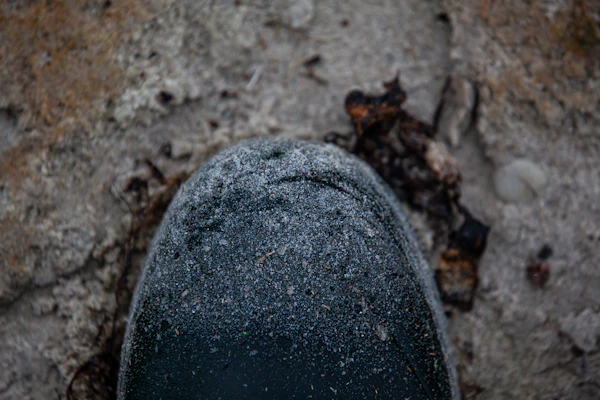 Close-up of a rugged work boot stepping on gravel, dust swirling around.