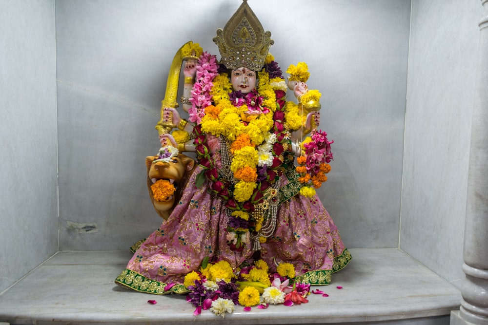 a statue of a hindu god with flowers around his body