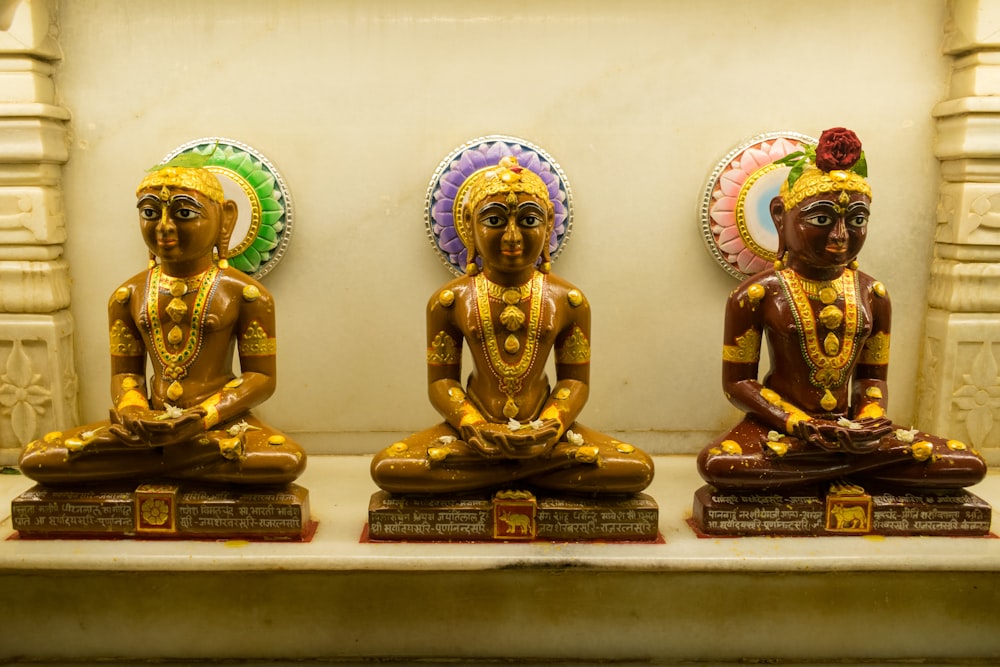 three statues of buddhas sitting in front of a wall