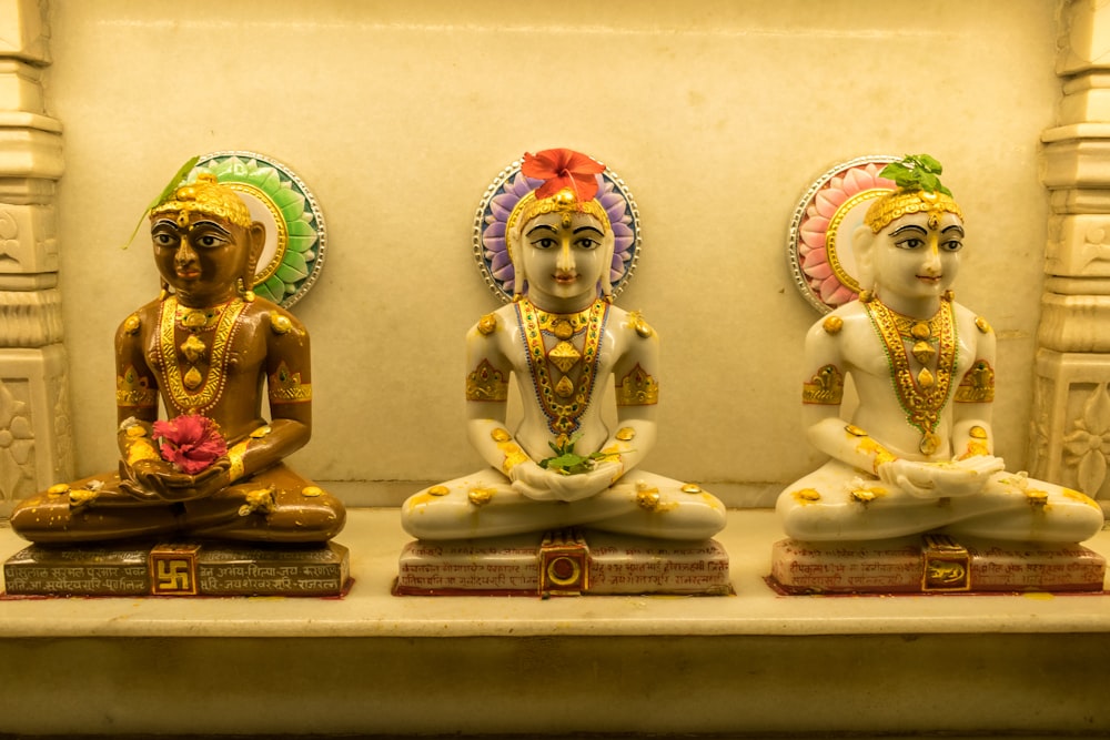three statues of hindu deities sitting in a row