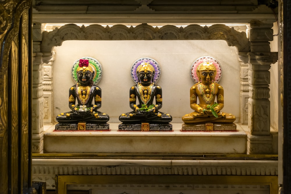 three statues of buddhas on display in a temple