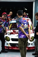 A group of friends wearing different custom car shirts, standing by their vintage cars.