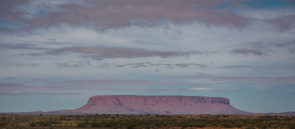 a large mountain in the distance under a cloudy sky