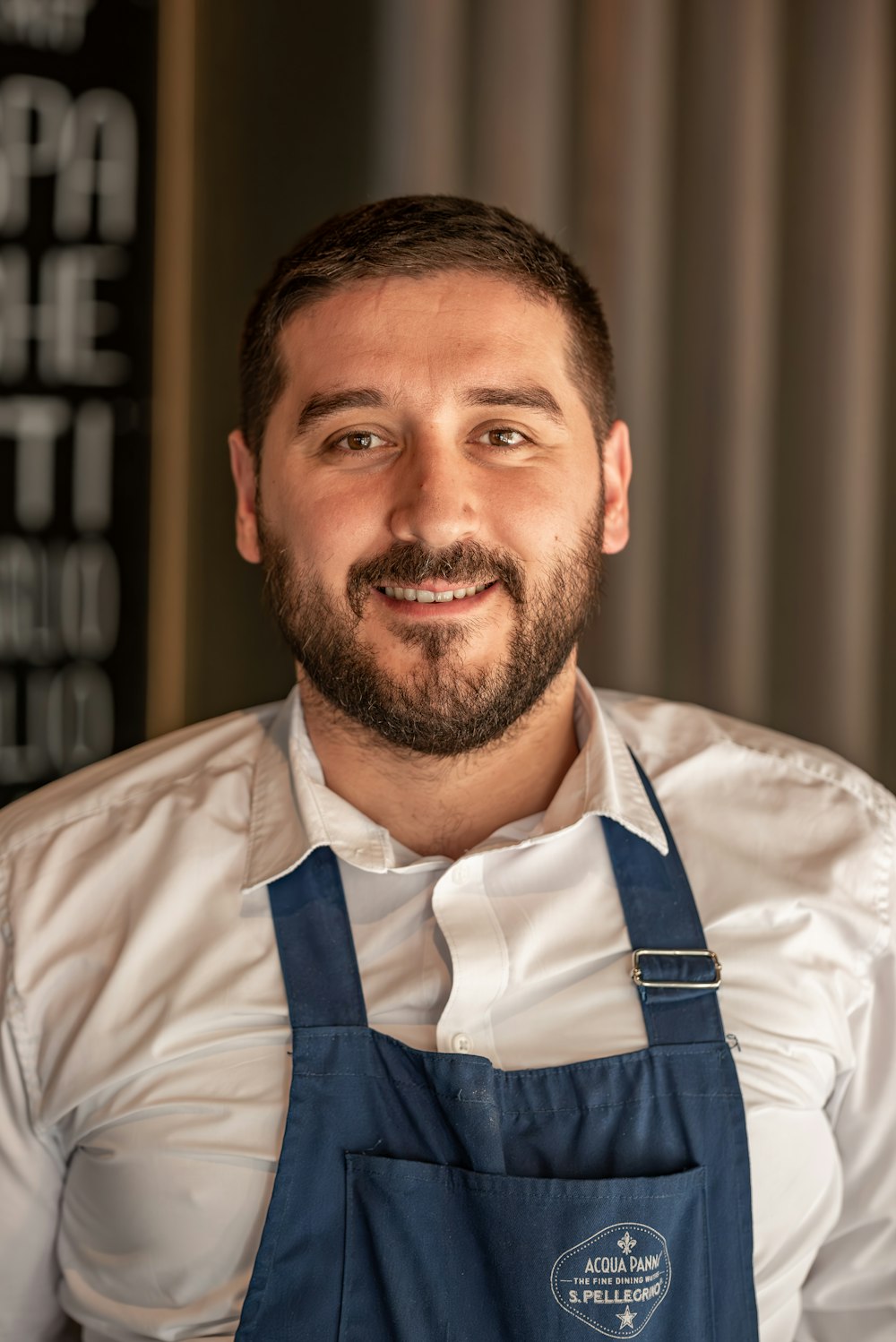 a man with a beard wearing a blue apron