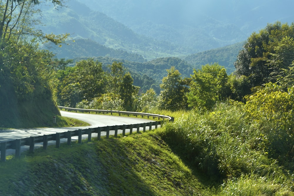 a curved road in the middle of a lush green hillside