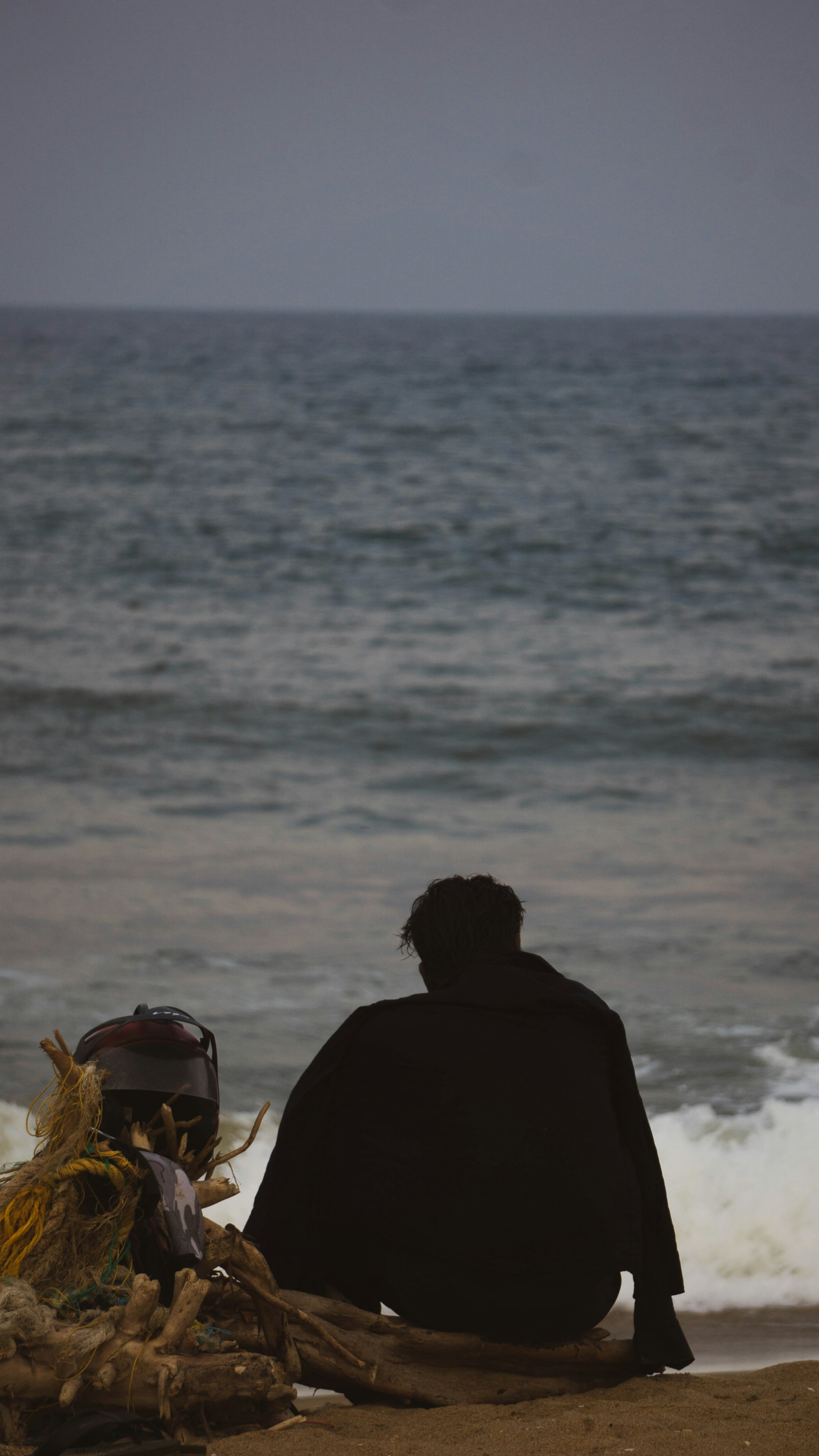 a man sitting on a beach next to the ocean