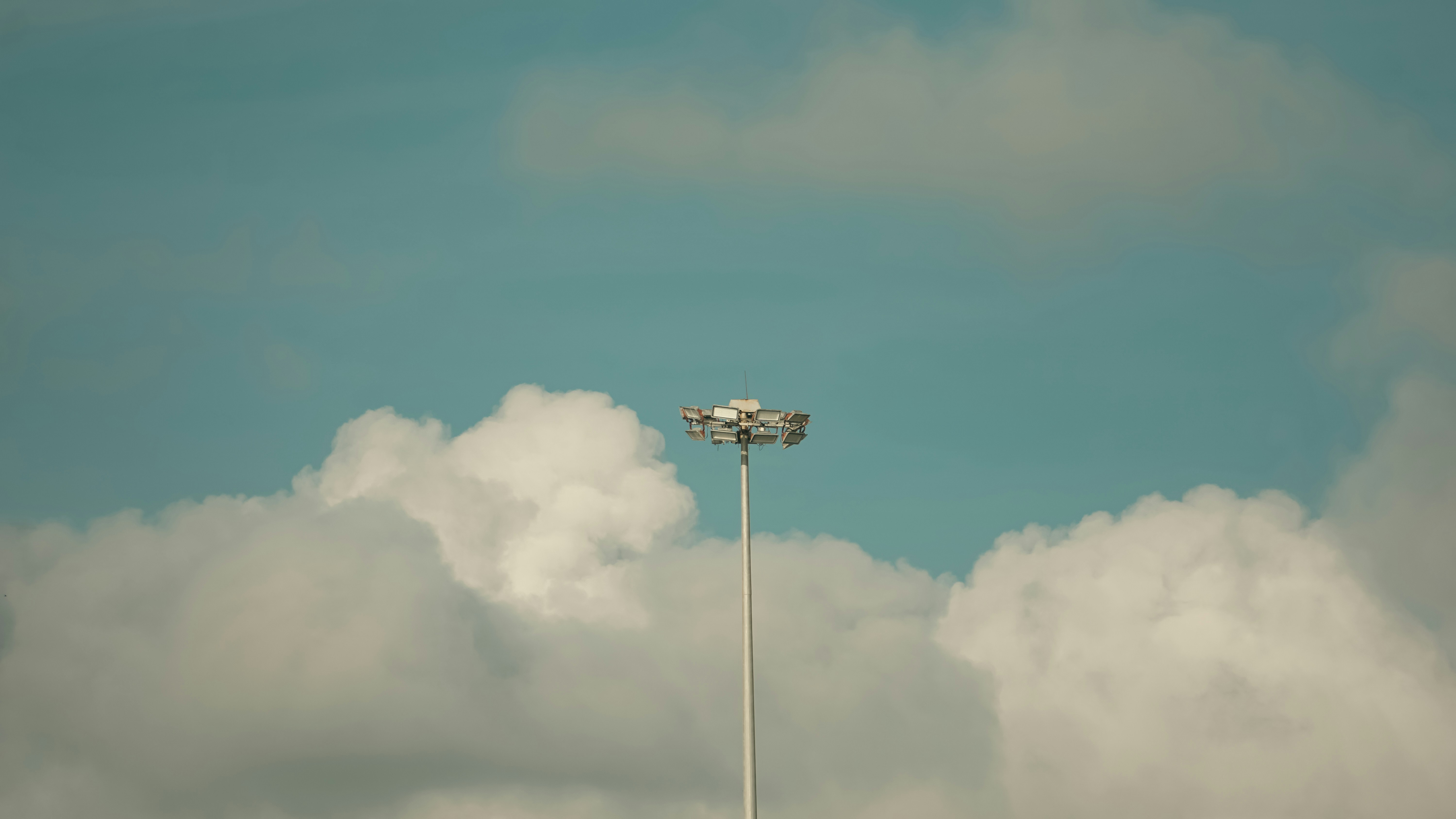 a tall light pole sitting under a cloudy blue sky