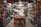 A small, crowded shop filled with a variety of packaged food items. Shelves are stacked with nuts, snacks, and other edible goods in jars and plastic bags. The shop has a narrow aisle leading to the back where more products are visible, including colorful bags and boxes.