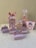 A collection of decorative party favor boxes with a circus theme featuring cartoon characters. They are adorned with images of girls in circus attire and small elephants wearing hats. The boxes are primarily pink with accents of white and light purple, some featuring star patterns. A large pink bow is prominent on one of the boxes.