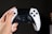 Close-up of hands holding a game controller with colorful game graphics on screen.