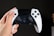 Close-up of hands holding a game controller with colorful game graphics on screen.