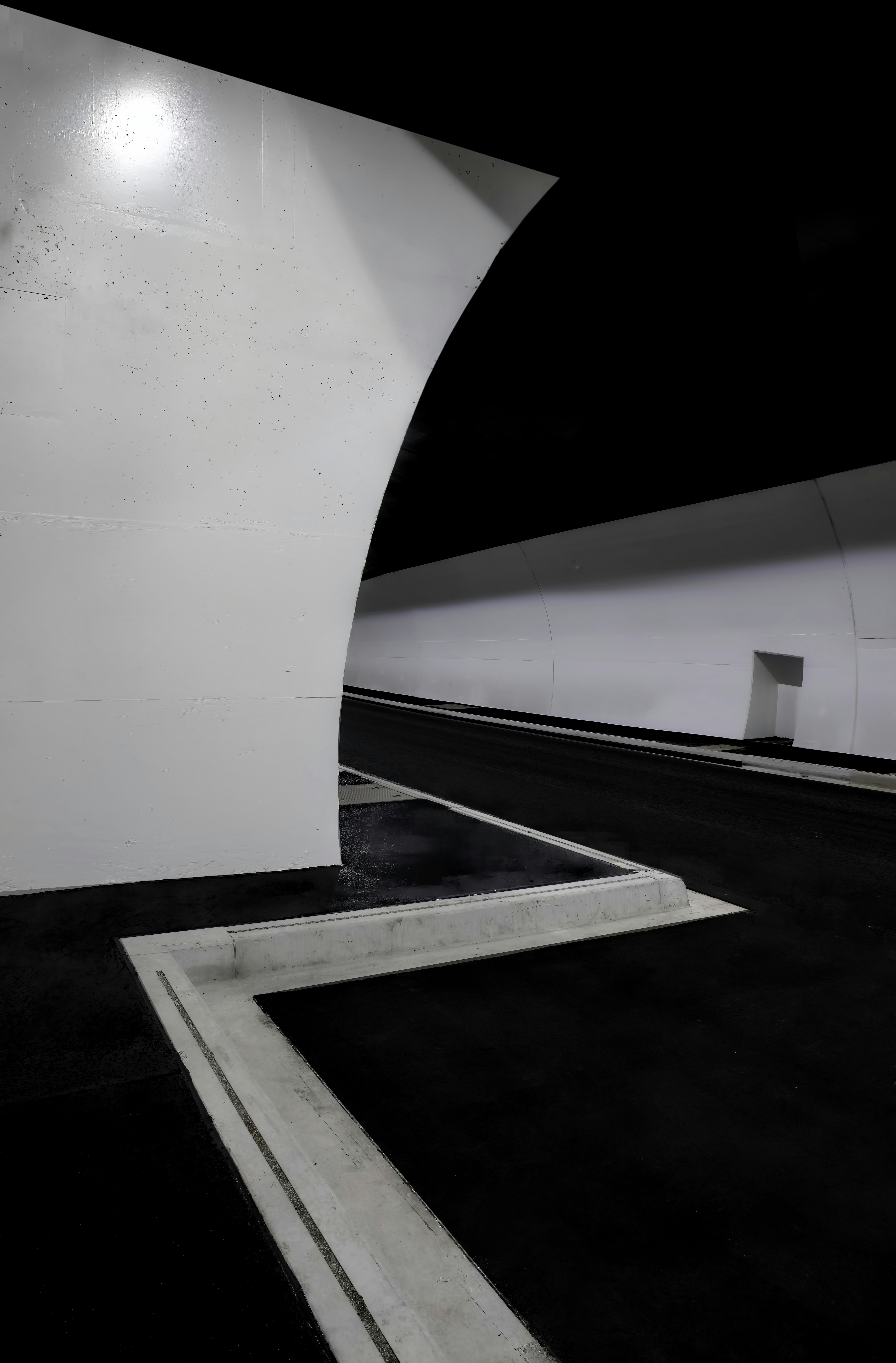 Un lunghissimo tunnel bianco con pavimento nero