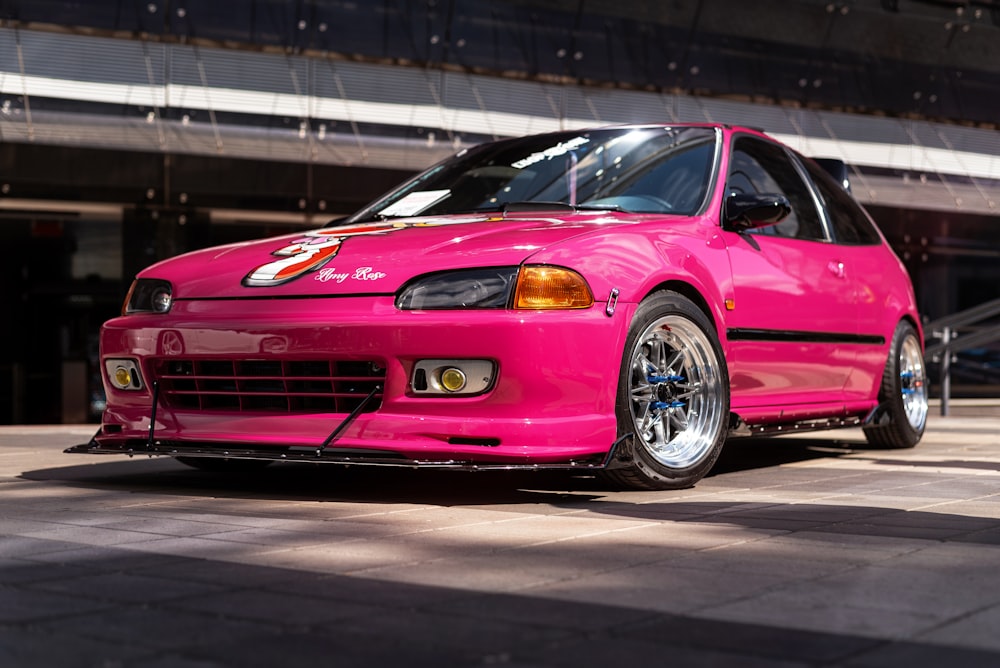 a pink car parked in front of a building