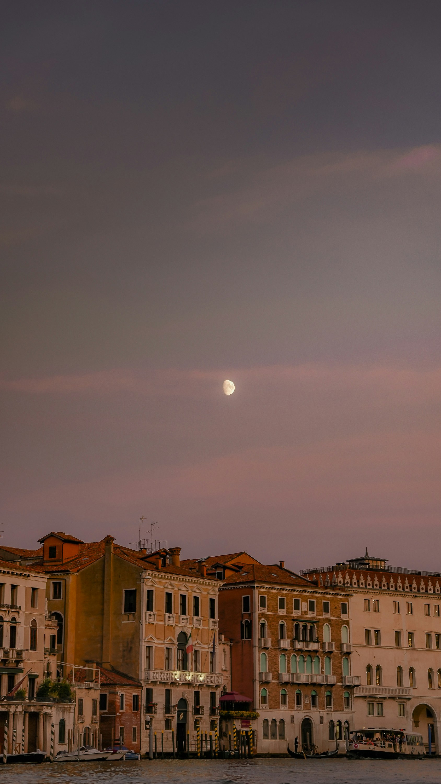Ein Vollmond ist über einer Reihe von Gebäuden zu sehen