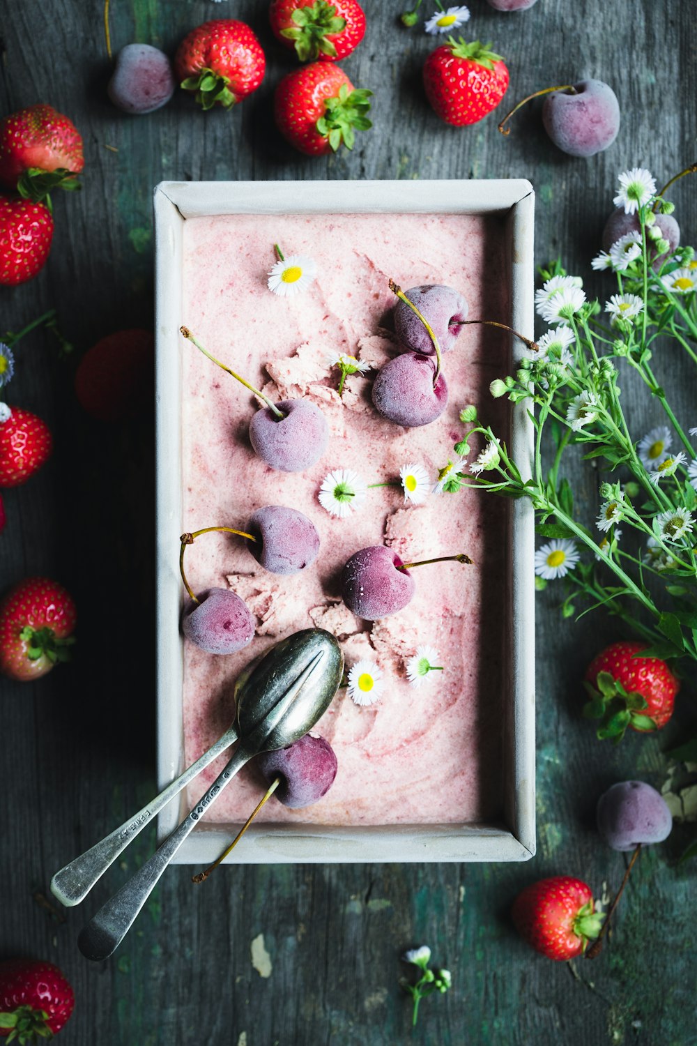 a bowl of ice cream with strawberries and flowers