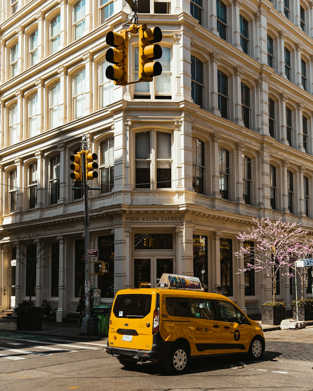 a yellow van is parked in front of a tall building