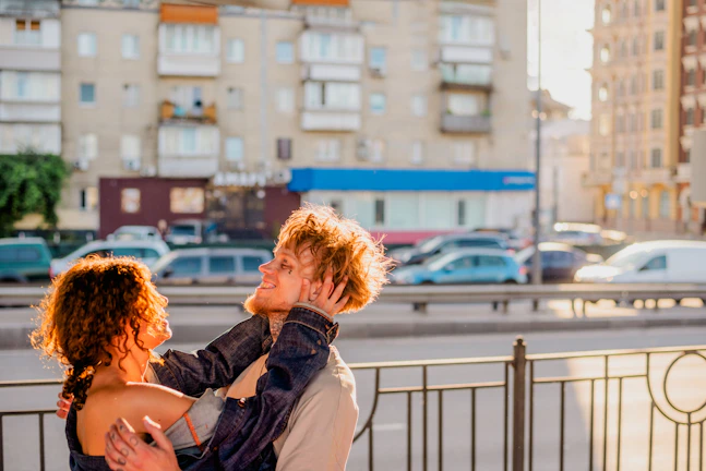 A candid sunlit portrait of a couple sharing a quiet, joyful moment on a terracotta-stained porch.