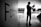 A silhouette of a person holding a phone stands in a spacious, modern interior with large windows allowing natural light. On the left, a wall displays the word 'Fotografia'. The atmosphere is serene with a focus on photography.