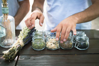 a person putting herbs in small glass jars