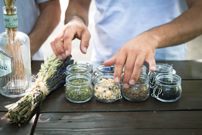 a person putting herbs in small glass jars