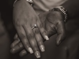 Close-up of their intertwined hands showing their engagement rings.
