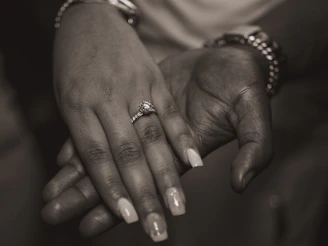 An artistic photo of hands holding old class rings and memorabilia.