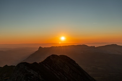 the sun is setting over a mountain range