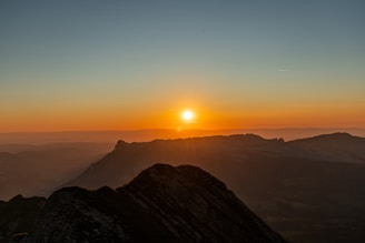the sun is setting over a mountain range