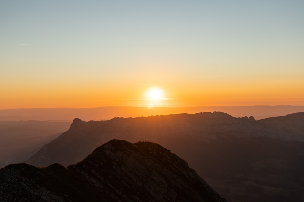 the sun is setting over a mountain range