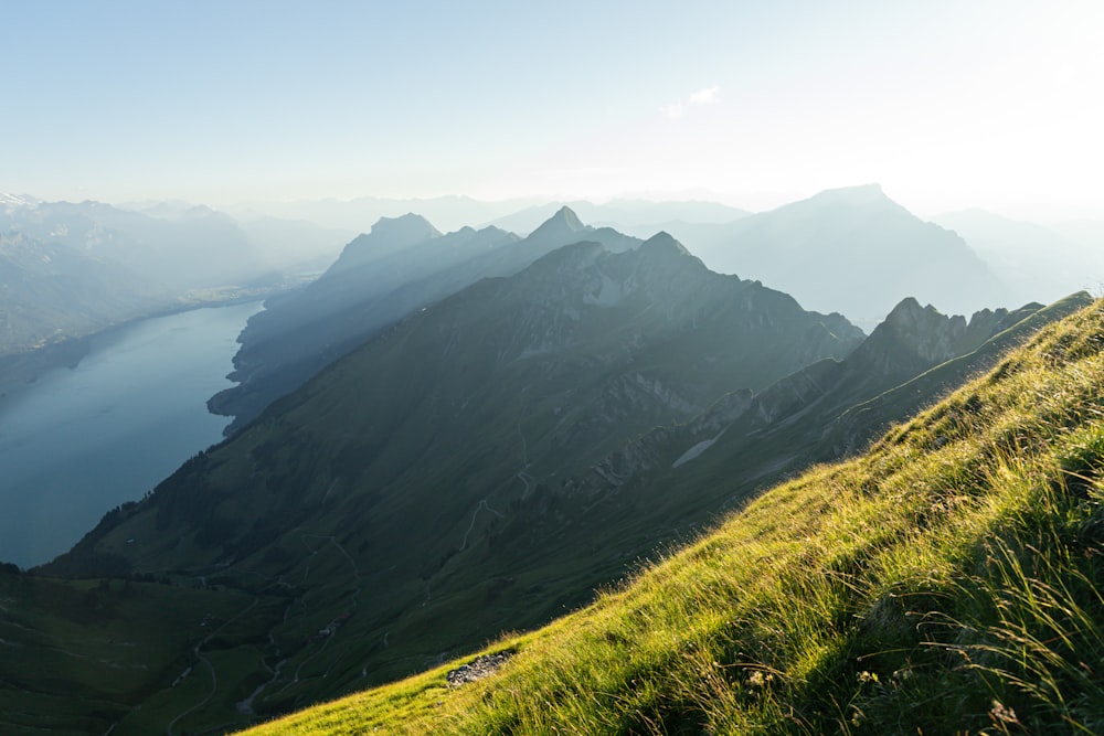 a grassy hill with a body of water in the distance