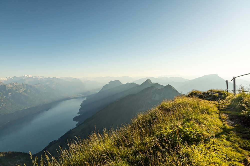 a grassy hill with a lake in the distance