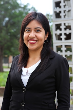 A woman in her 40s wearing a comfortable yet elegant blouse, standing outdoors.