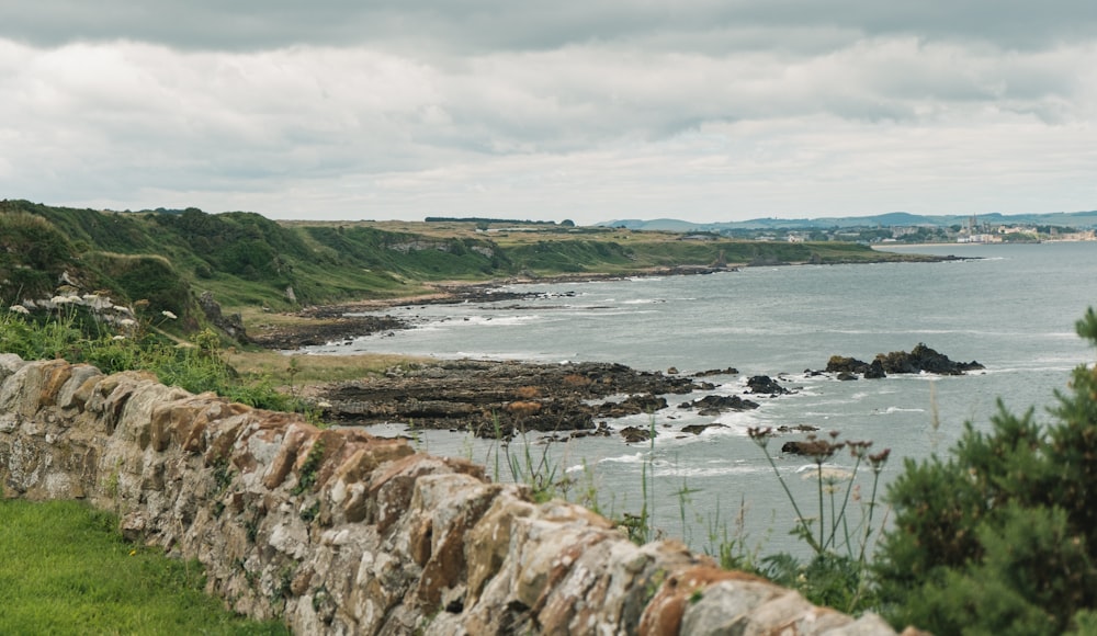 a stone wall next to a body of water