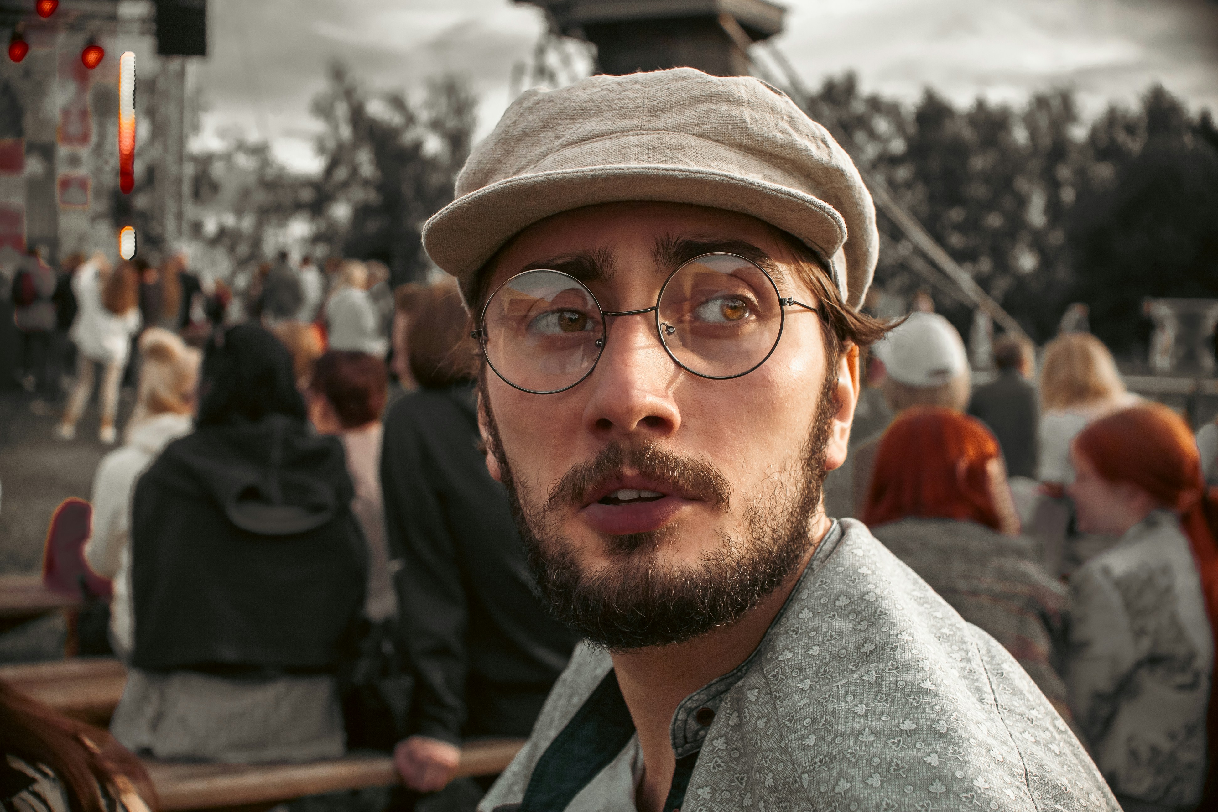 a man with glasses and a hat standing in front of a crowd