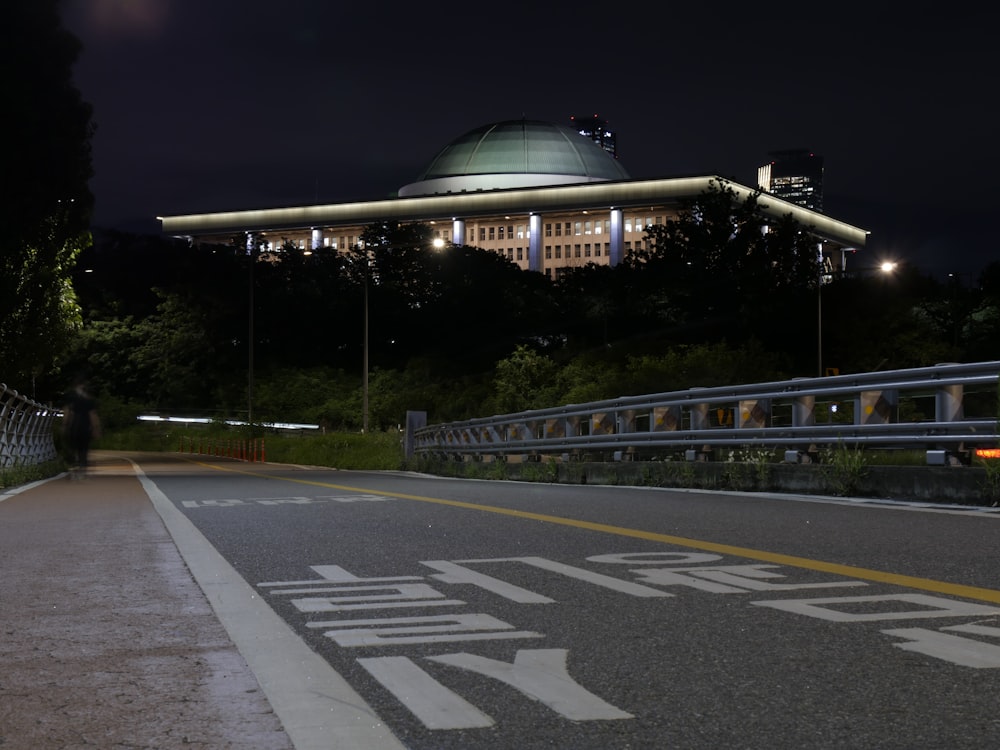 a city street at night with a building in the background