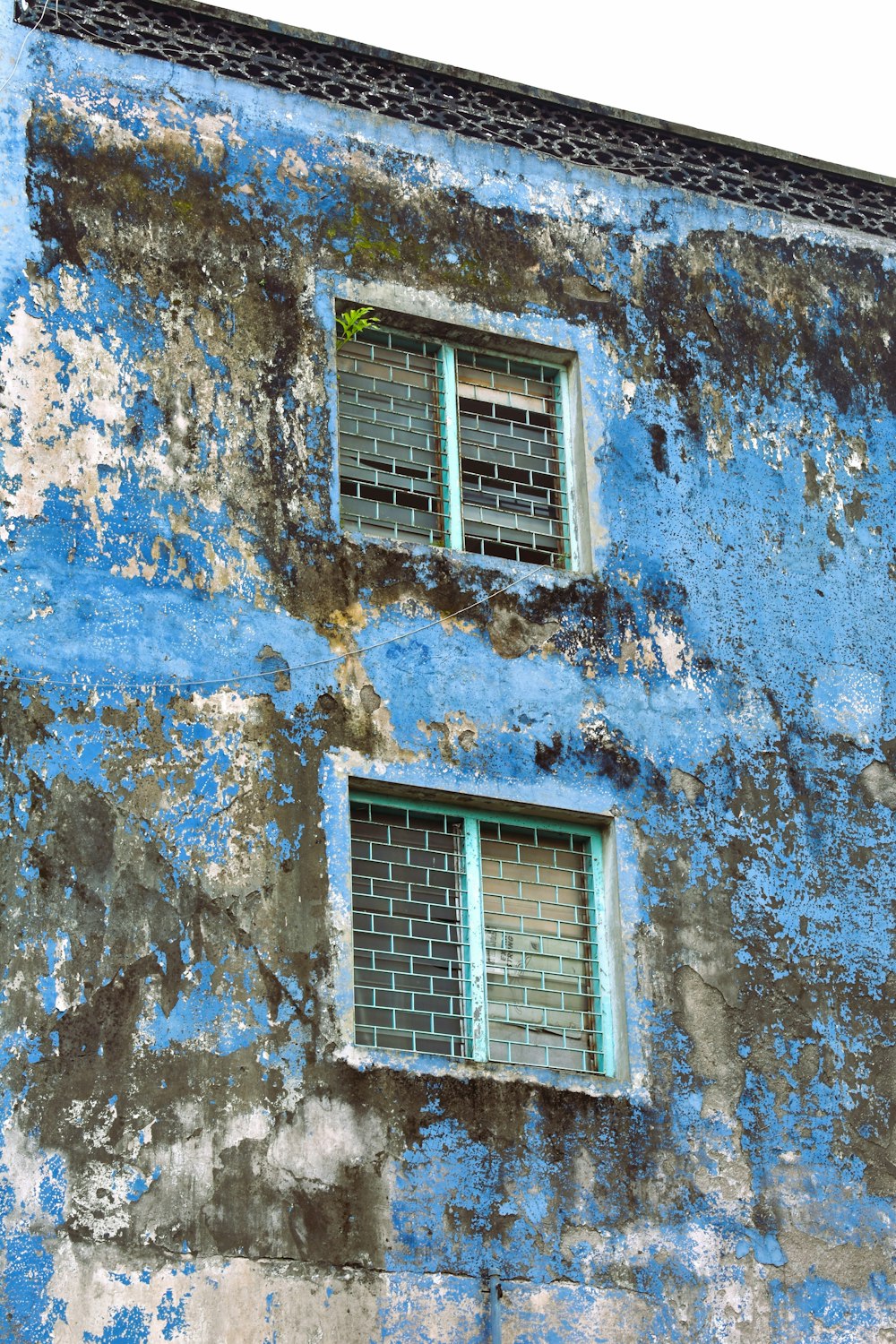 a blue building with two windows and a clock