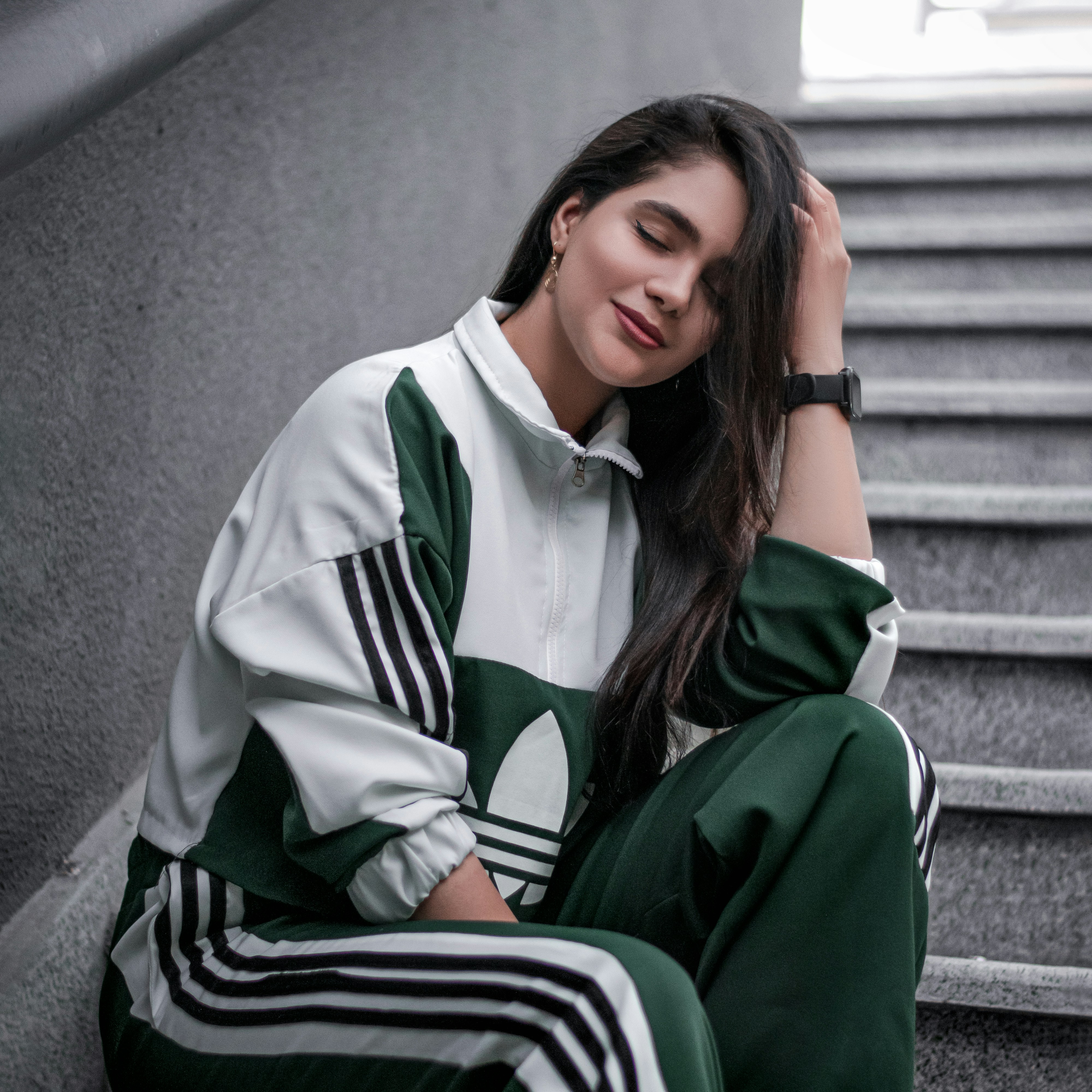 a woman sitting on the steps wearing a green and white track suit