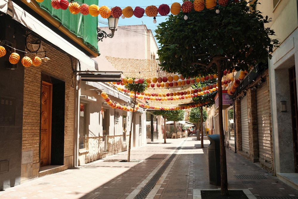 a narrow street with lanterns hanging from the ceiling