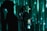 A person with long hair is looking upwards while standing in front of a green digital-like background. The lighting casts dramatic shadows and patterns across both the figure and the background, creating an atmosphere reminiscent of a digital matrix.