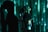 A person with long hair is looking upwards while standing in front of a green digital-like background. The lighting casts dramatic shadows and patterns across both the figure and the background, creating an atmosphere reminiscent of a digital matrix.