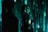 A person stands in profile against a backdrop of cascading green digital code, reminiscent of a futuristic or cyberpunk aesthetic. The person is wearing dark clothing with visible logos and has long hair. Shadows and green light interplay across their face and body, creating a mysterious atmosphere.