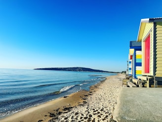 Brighton & Hove seaside view with colorful beach huts under a clear blue sky.