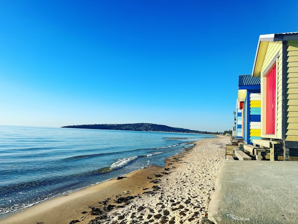Brighton & Hove seaside view with colorful beach huts under a clear blue sky.