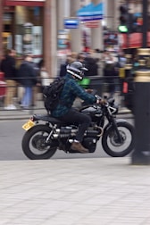 A motorcycle rider with a tracking device mounted, riding through urban traffic.