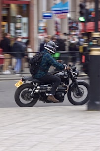 A motorcycle rider with a tracking device mounted, riding through urban traffic.