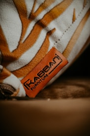 A detailed view of a textured surface featuring brown and white patterns, with a prominent leather tag embossed with the text 'Furniture'. The tag is placed on a soft fabric, contributing to a cozy aesthetic.
