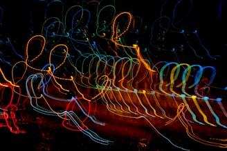 A dynamic display of colorful, looping light trails against a dark background, creating an abstract, energetic pattern with a sense of motion.