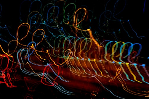 A dynamic display of colorful, looping light trails against a dark background, creating an abstract, energetic pattern with a sense of motion.